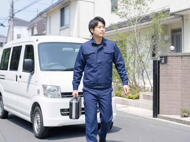サービス車両から工具を持って訪問するエアコン修理スタッフ